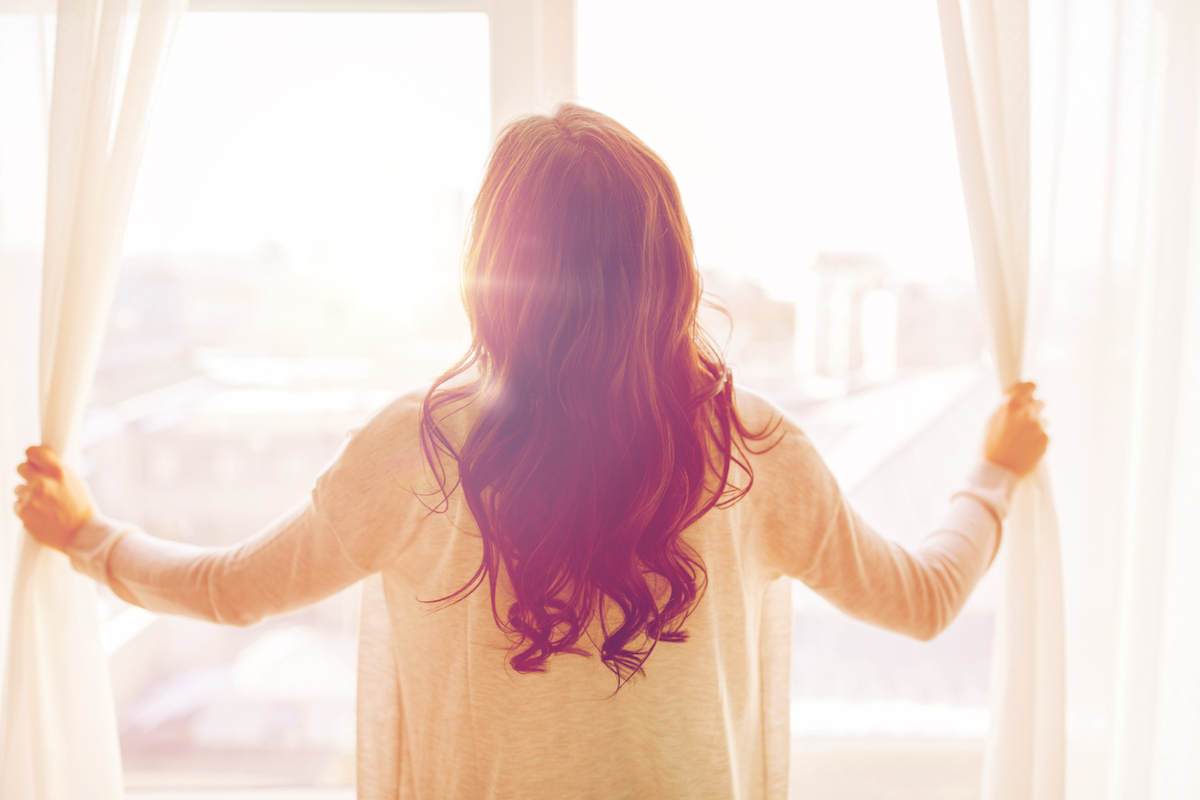 Woman opening the curtains in the morning