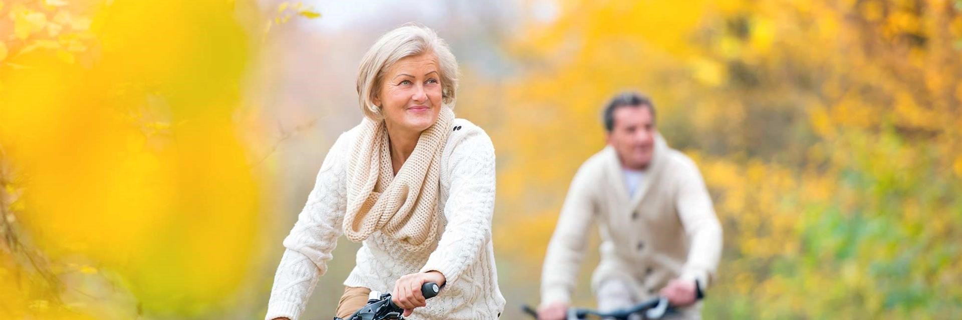 Older couple cycling through yellow flowers
